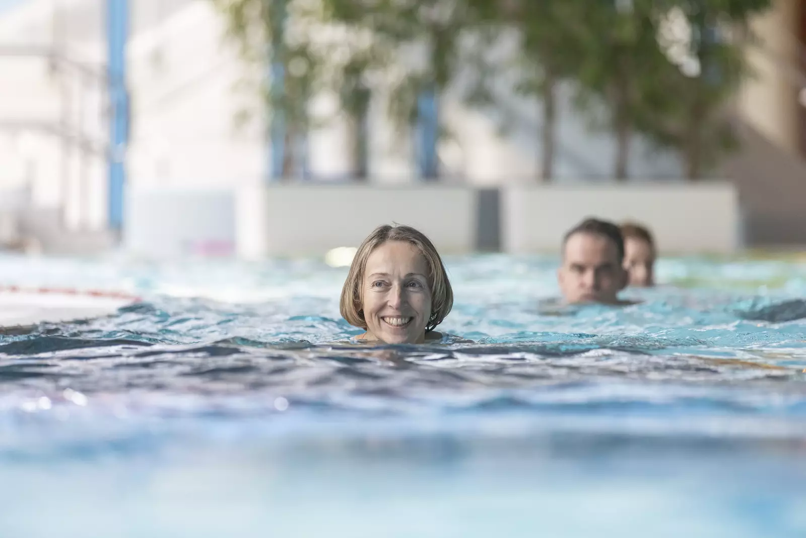 Eine Frau im Vordergrund einer Schwimmergruppe schwimmt im Erlebnis-Innenbecken im LEUZE
