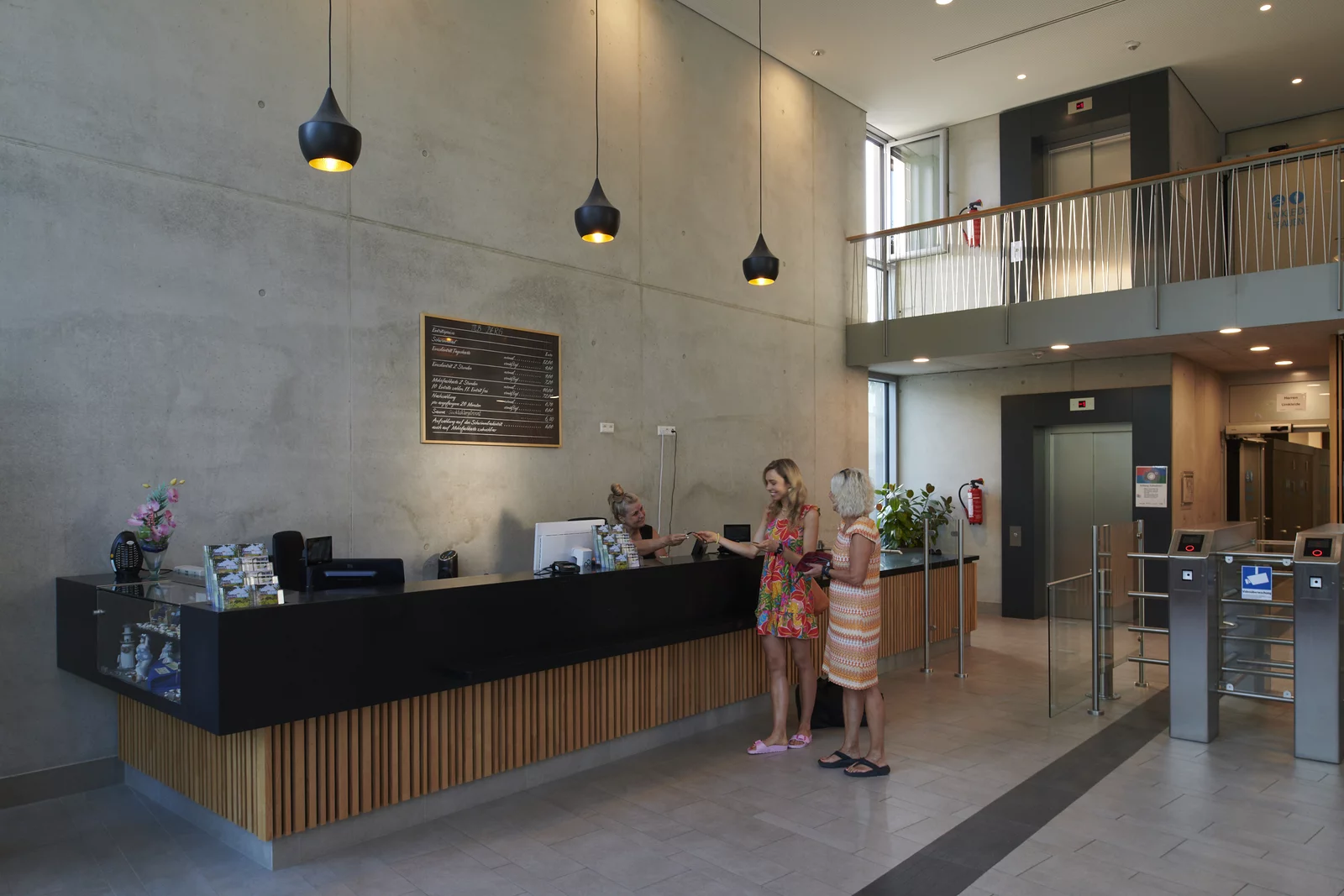 Kasse im Foyer Mineralbad Berg Zwei Frauen kaufen Eintrittstickets an der Kasse im Foyer im Mineralbad Berg.