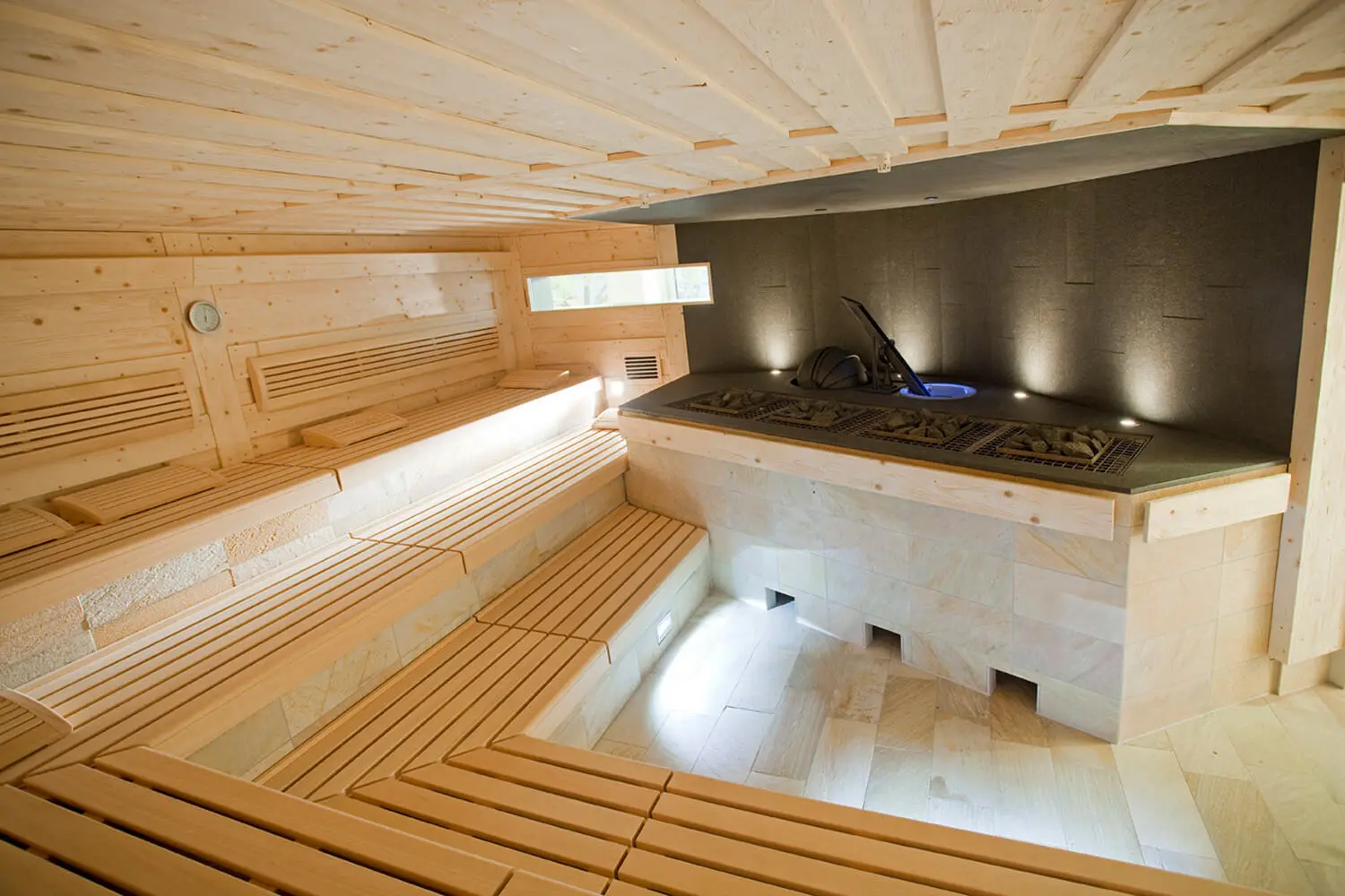 Innenansicht Sauna im LEUZE: Holzbänke und Aufgussbereich ohne Besucher.