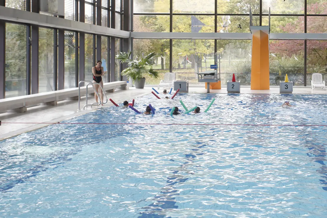 Kinder mit Schwimmnudeln nehmen an einem Schwimmkurs im Schwimmerbecken im Hallenbad Vaihingen teil.