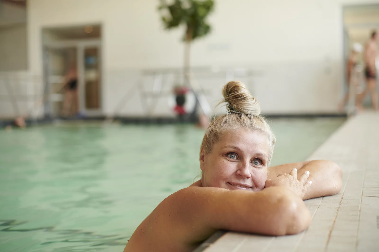 Bewegungsbad Mineralbad Berg Eine Frau ruht sich am Beckenrand aus.