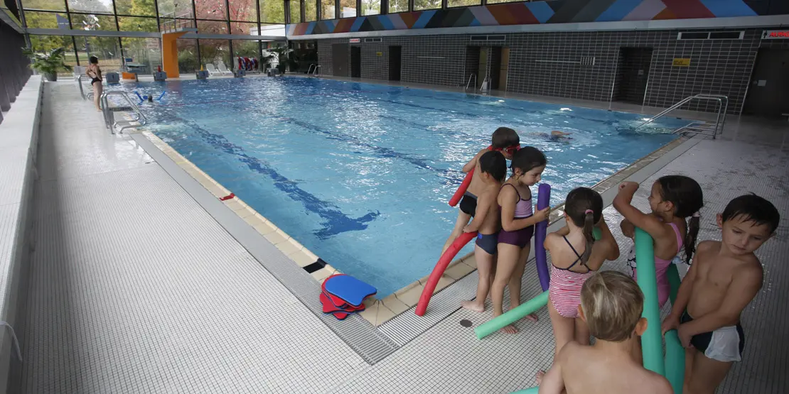Ein Kinderkurs mit Schwimmnudeln steht am Beckenrand im Hallenbad Vaihingen.